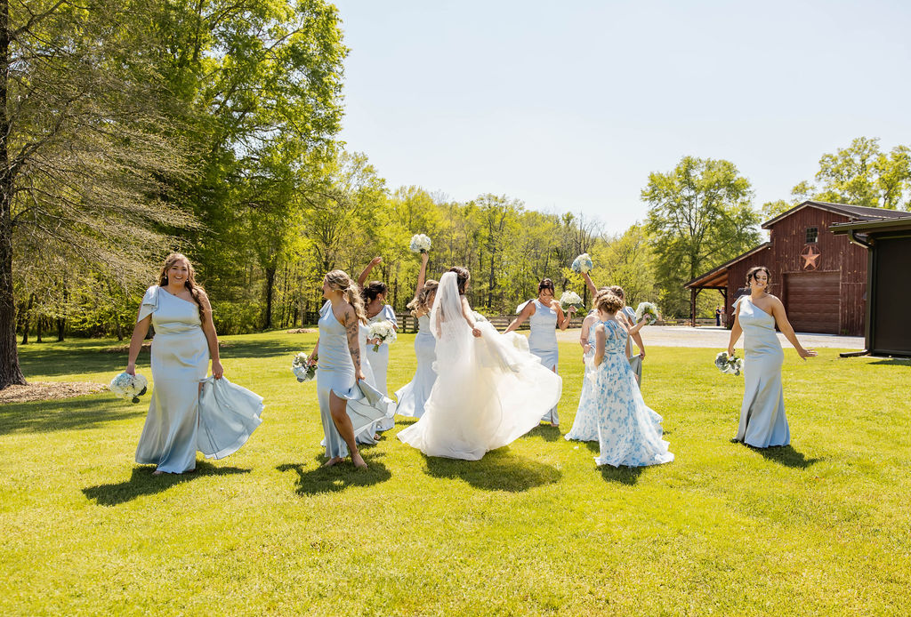 Shelbie & Callaway: bride Shelbie twirls with blue bridesmaids on the lawn before the barn at Covey Creek