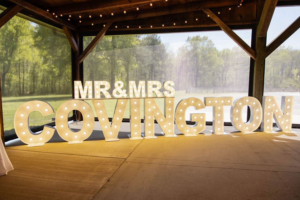Shelbie & Callaway MR & MRS COVINGTON marquee letters glowing under the pavilion string lights at Covey Creek