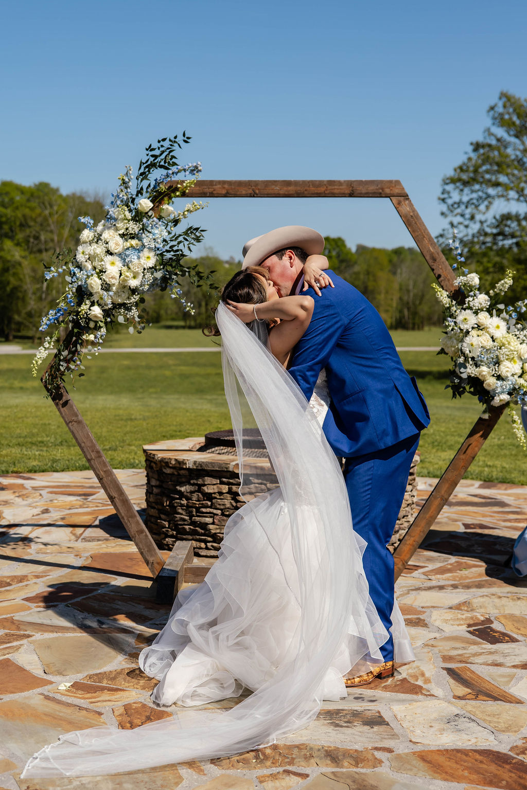 Shelbie & Callaway kiss under a floral hexagonal arbor at the Covey Creek Firepit outdoor ceremony site