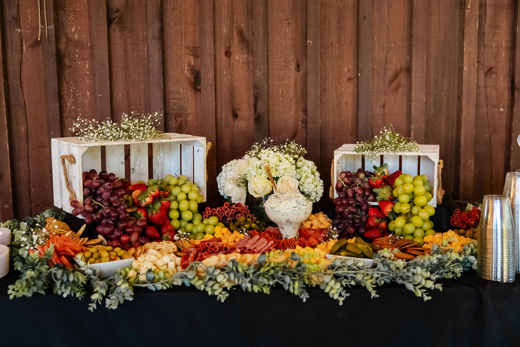 Shelbie & Callaway charcuterie and fruit grazing table with white florals against wood walls at Covey Creek