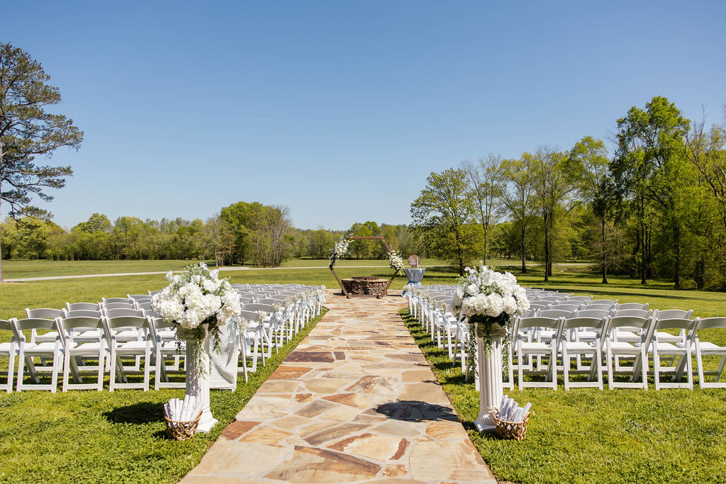 Shelbie & Callaway Firepit ceremony setup at Covey Creek with stone aisle, white chairs, and floral hex arbor
