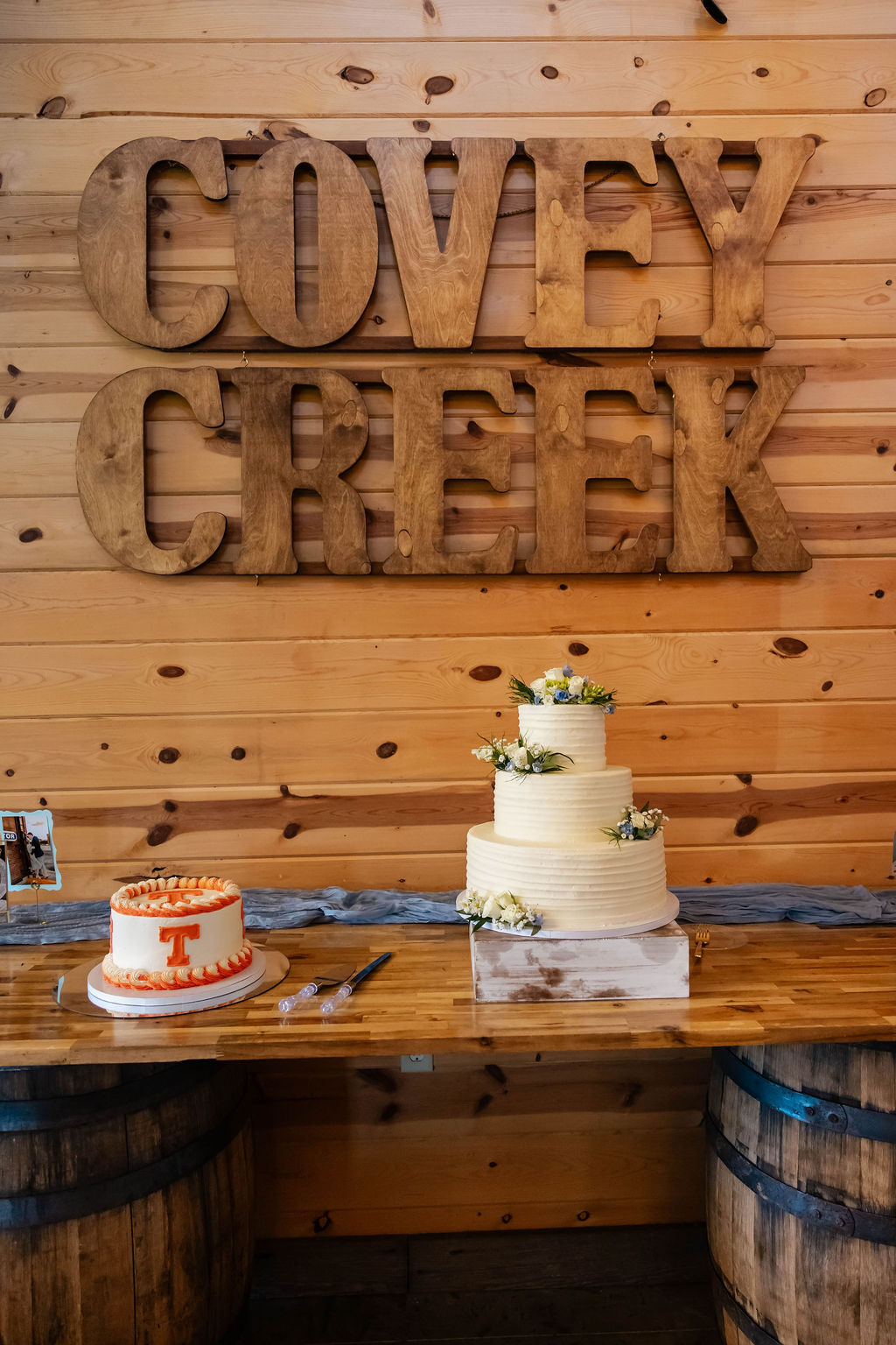 Shelbie & Callaway ribbed wedding cake and UT Vols groom's cake on barrel table under Covey Creek wood letters
