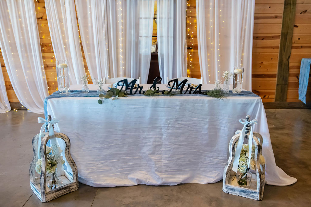 Shelbie & Callaway Mr & Mrs sweetheart table with lantern florals and fairy-lit curtains at Covey Creek