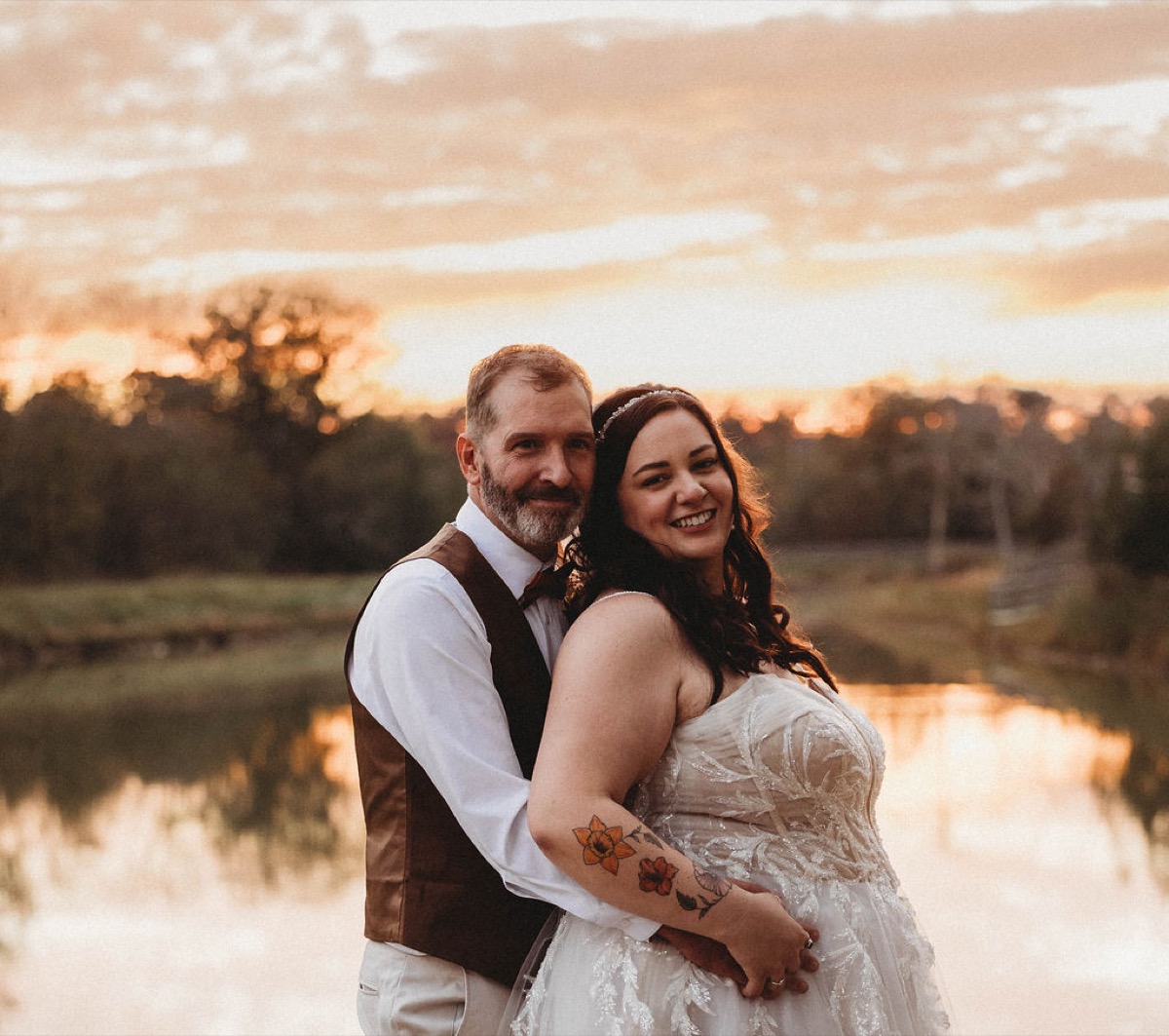 Tori & Tim smile in a close embrace beside the Pond reflecting a golden sunset at Covey Creek