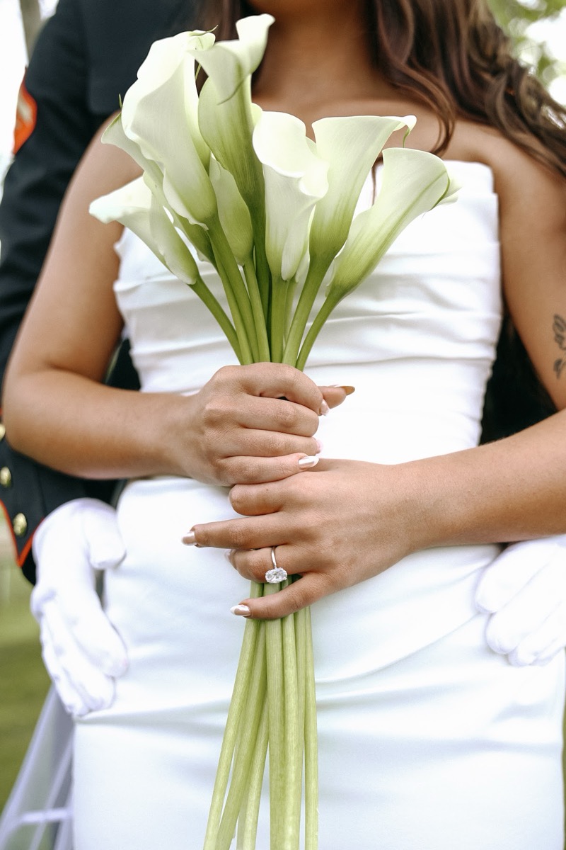 Close detail of Cadence & Brody: calla lilies, her ring, and his white-gloved hands at Covey Creek