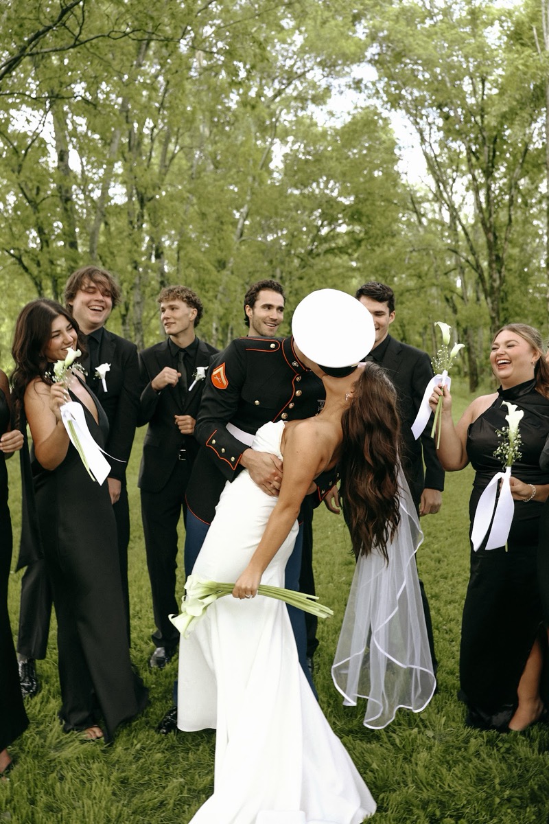 Cadence & Brody dip-kiss as their black-clad wedding party cheers on the lawn at Covey Creek