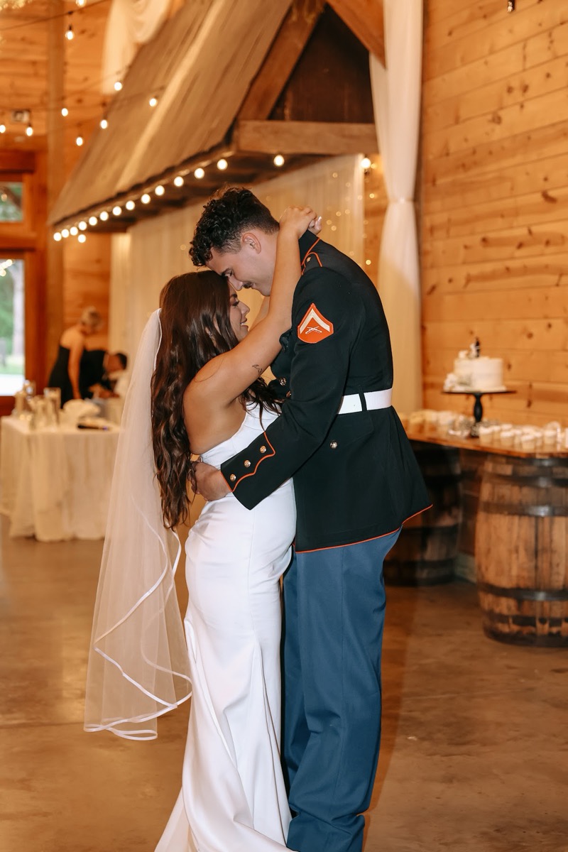 Cadence & Brody share a forehead-to-forehead dance by the barrel dessert table in the barn at Covey Creek