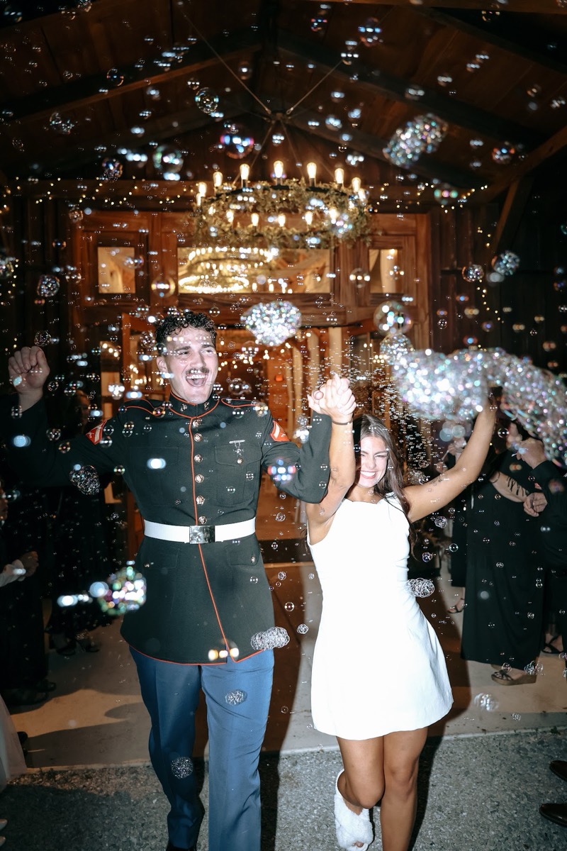 Cadence & Brody cheer through a bubble send-off from the barn doors at night at Covey Creek