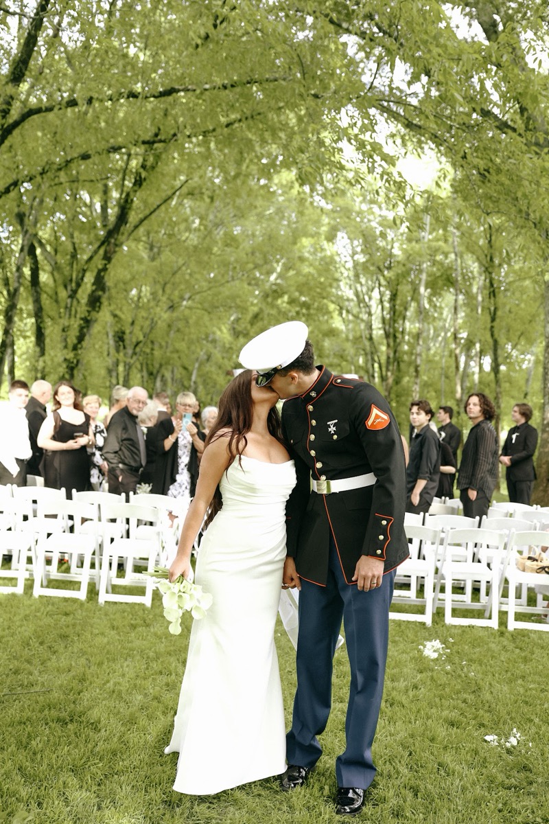 Cadence & Brody kiss on the grassy aisle after vows, Brody in Marine blues under trees at Covey Creek