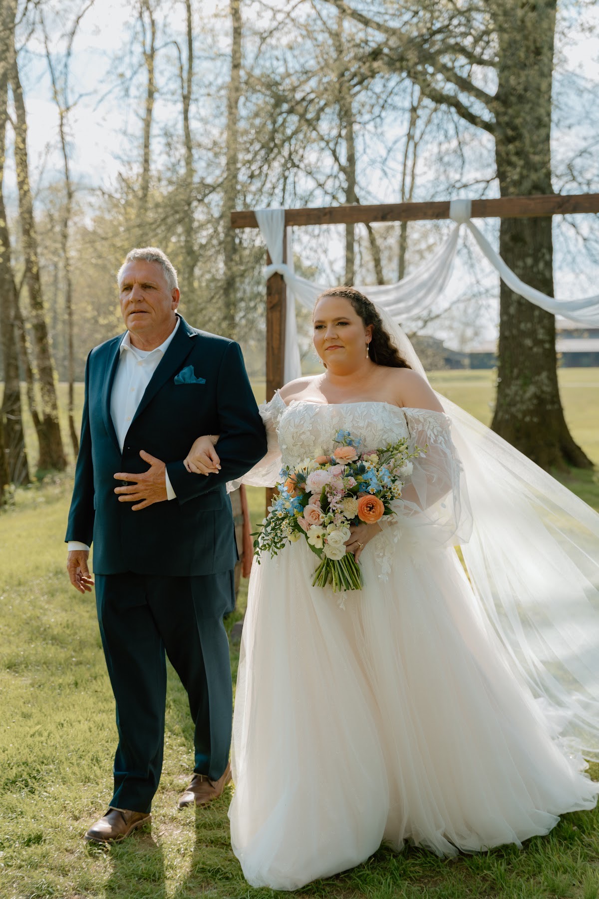 Katelynn walks the aisle with her father past a floral arbor at Covey Creek for Katelynn & Justin