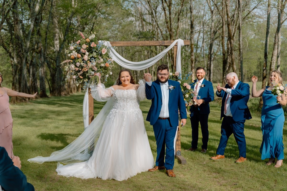 Katelynn & Justin cheer walking the aisle after vows, her lace gown and blue suit bright at Covey Creek