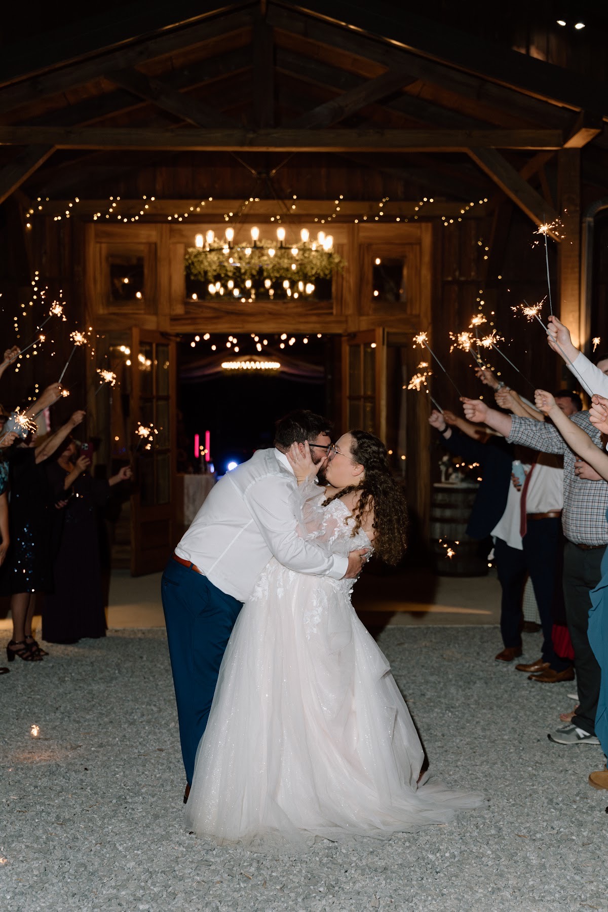 Katelynn & Justin kiss in a dip during their nighttime sparkler exit outside the barn at Covey Creek