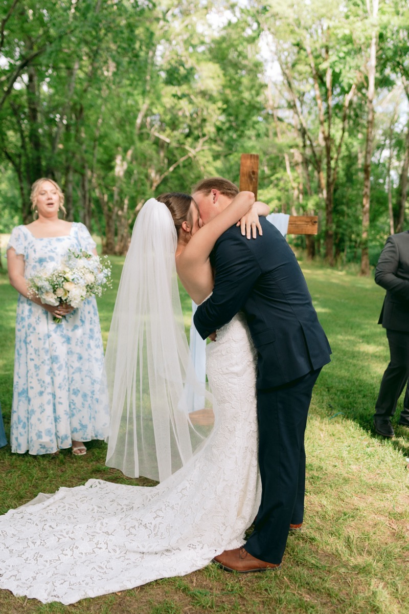 Rachel & Ben share their first kiss before a wooden cross under the Tunnel of Love canopy at Covey Creek.