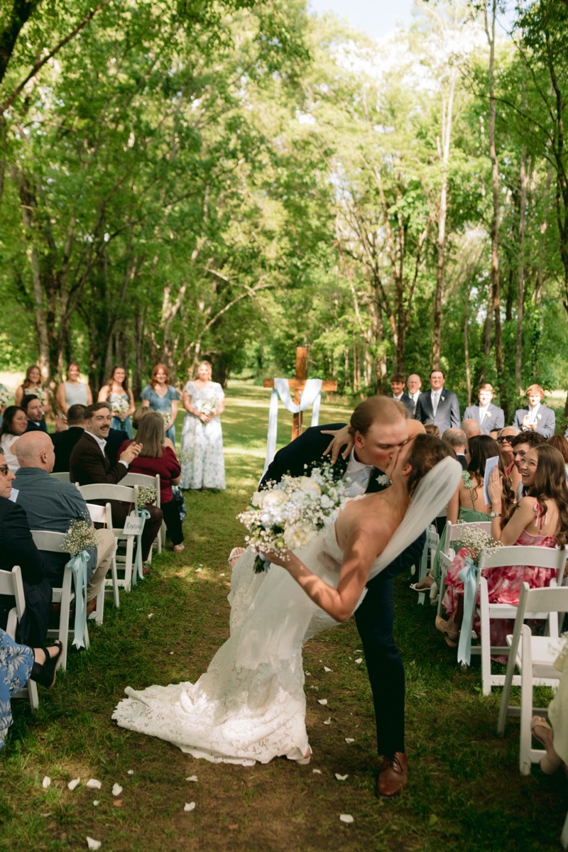 Rachel & Ben share a dip kiss in the grassy aisle under the Tunnel of Love canopy at Covey Creek.