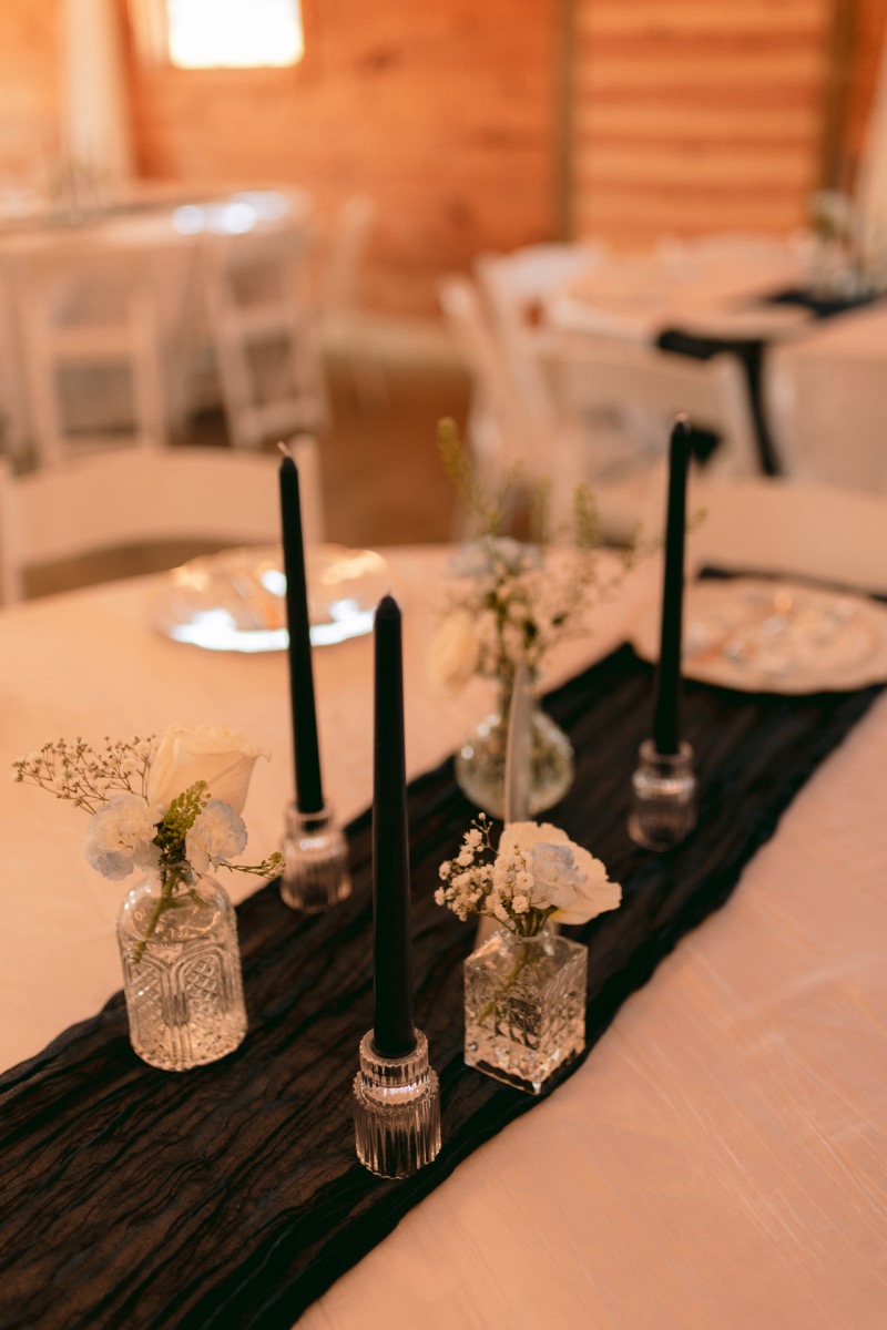 Rachel & Ben reception tablescape with black tapers, white roses, and baby's breath at Covey Creek.