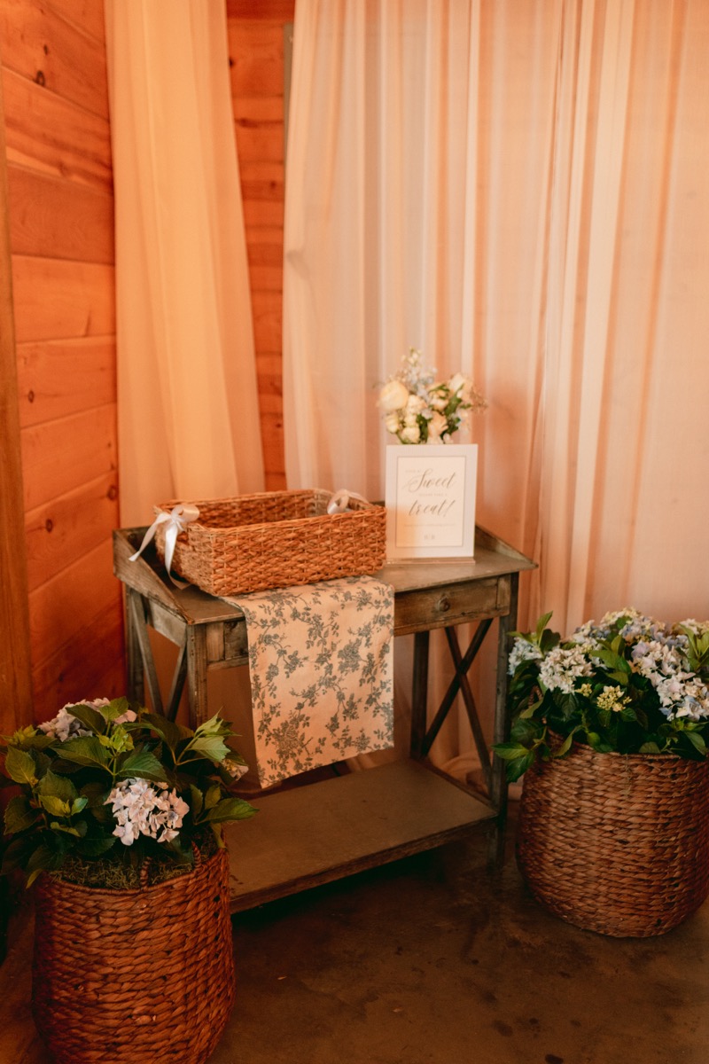 Rachel & Ben's indoor reception sweet-treat table with blue hydrangea baskets at Covey Creek.
