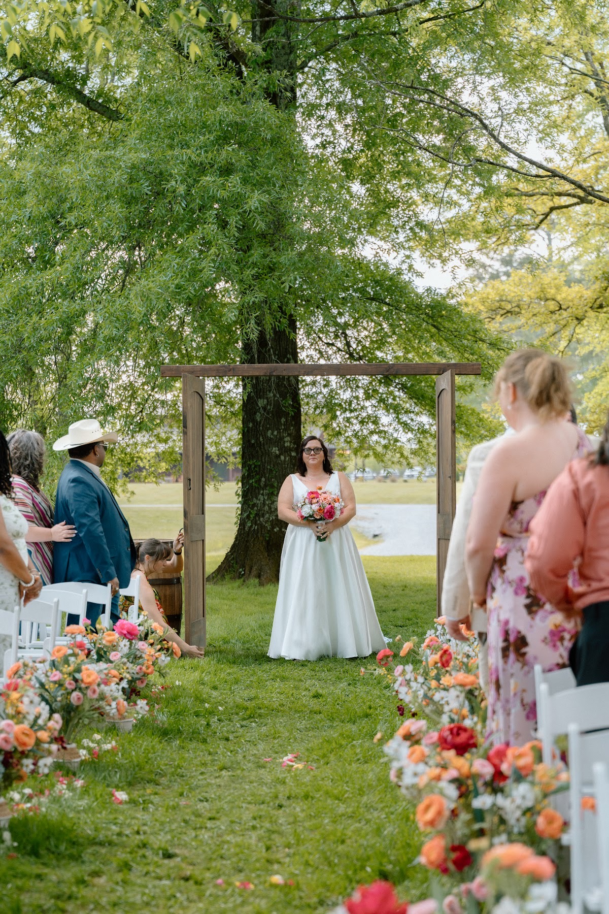 Stephanie holds her pink bouquet in the wooden doorway before the aisle walk with Josh at Covey Creek