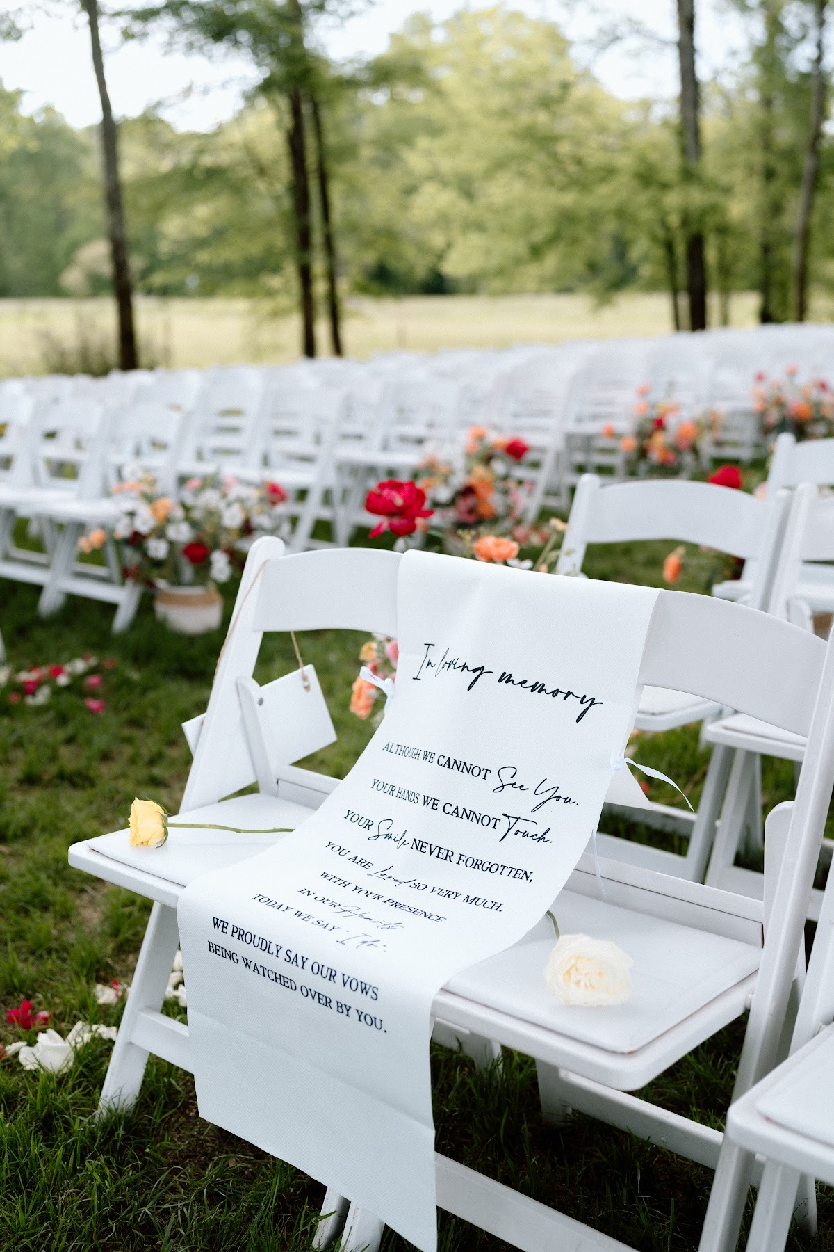 Memorial chair with roses and an In loving memory banner on the lawn for Stephanie & Josh at Covey Creek