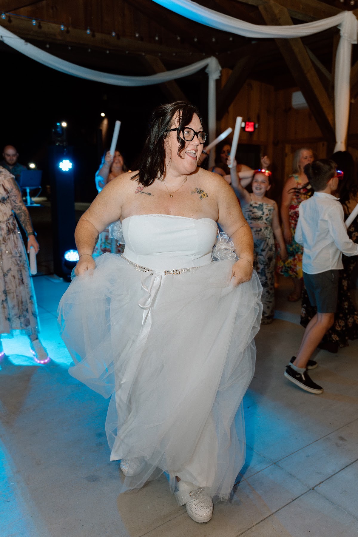 Stephanie dances in her gown and sparkly sneakers under pavilion lights for Stephanie & Josh at Covey Creek