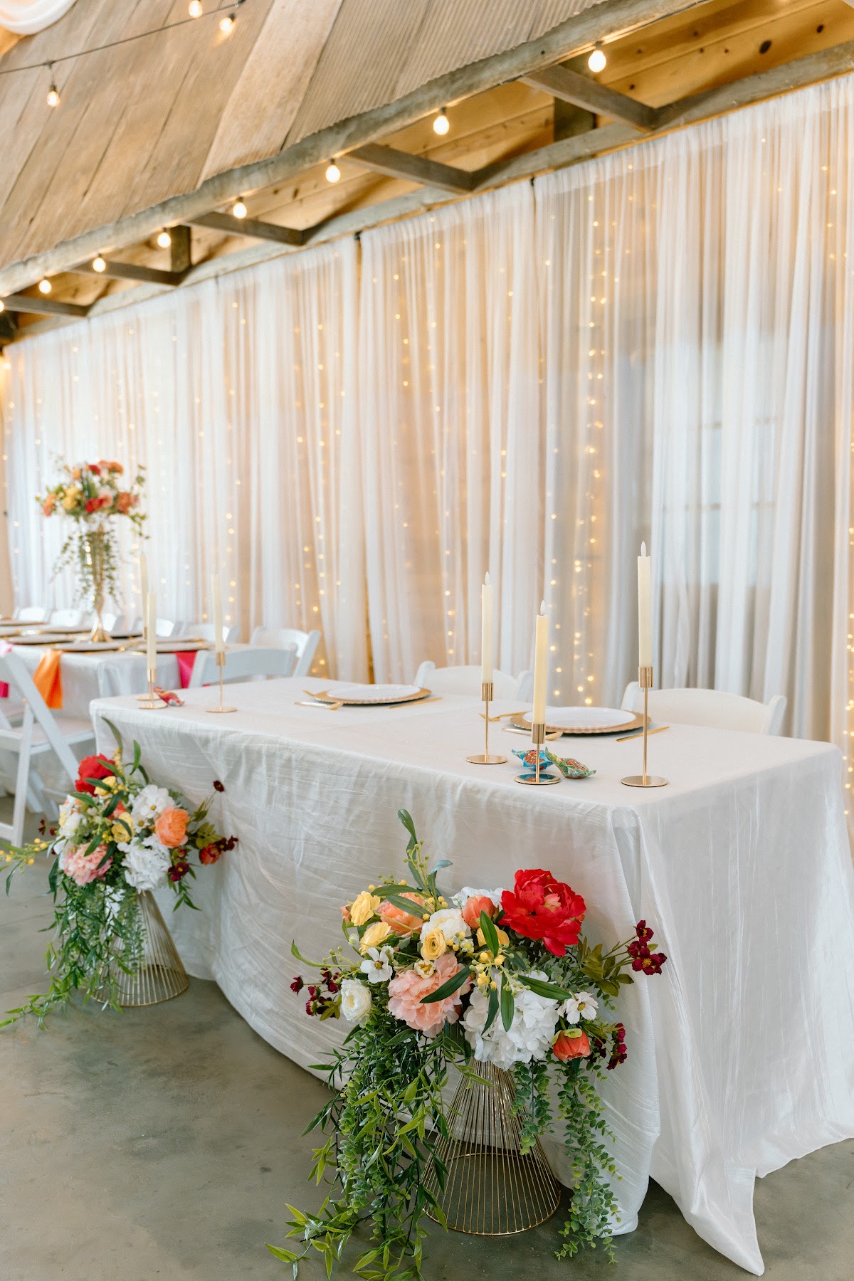 Stephanie & Josh's sweetheart table with gold candles and floor florals before lit curtains at Covey Creek